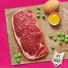 A cut of raw beef lays on brown paper alongside eggs and peas