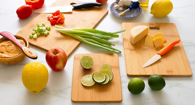 3 bamboo cutting boards being used to cut food in the kitchen