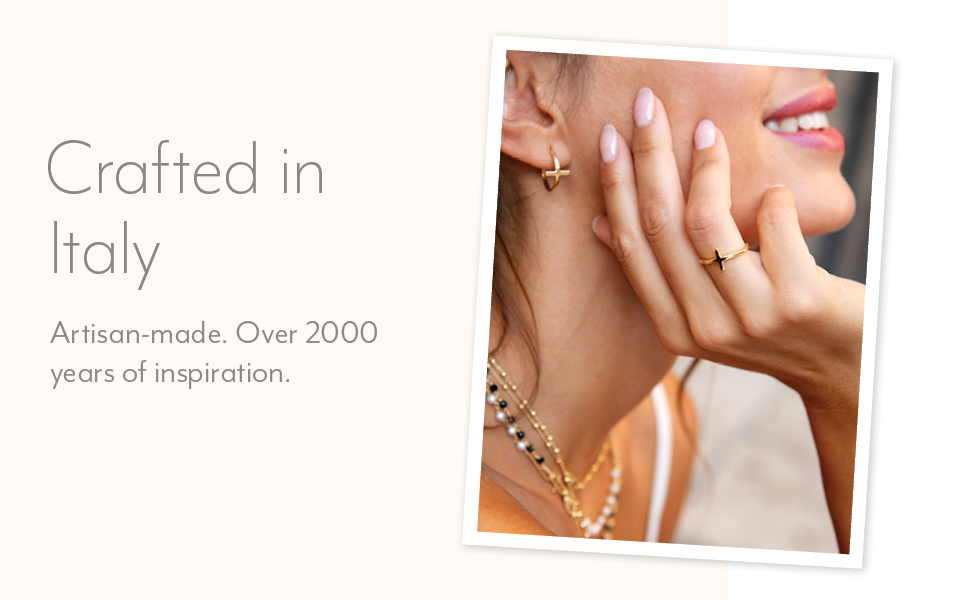 Woman wears gold plated silver cross ring and earrings and layered necklaces. 