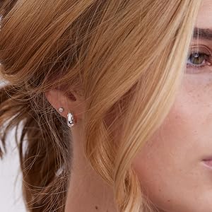 Model wearing shiny silver plated huggie hoops